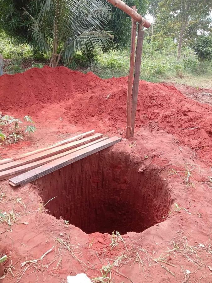 A newly dug well shaft in red earth, with timber ready for the well head