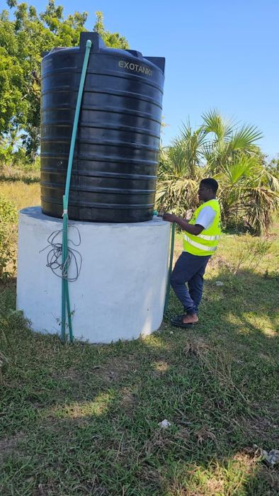 A Helping Hands volunteer checking the tap on a water tank installed on a completed well